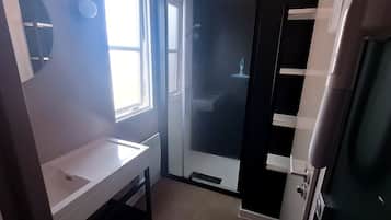 A bathroom with a white sink, a shower, and a door with a handle.
