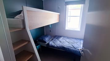 Une petite pièce avec un lit superposé, une fenêtre et une étagère intégrée.