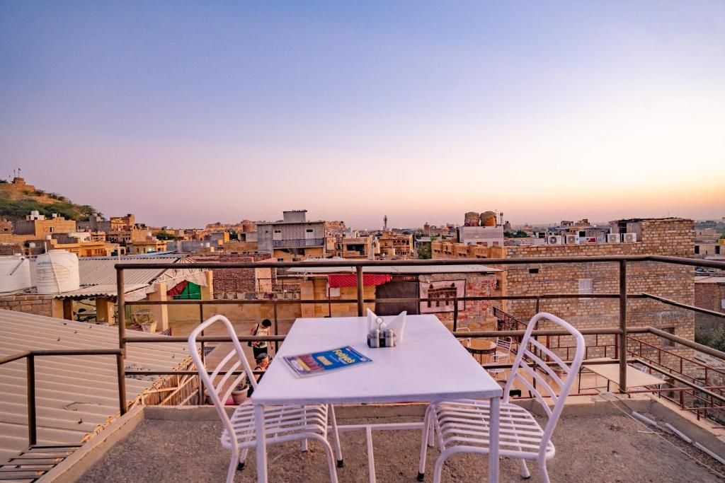 A rooftop terrace with a table and chairs, overlooking a cityscape.