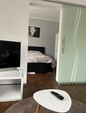 A modern bedroom with a bed, a TV, and a remote on a small table. - Vacation Rentals at the "Landgestüt," Apartment at the Landgestüt, 55 m², 1–3 people (Warendorf)