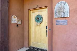 A wooden door with a welcome sign, a wreath, and a welcome sign on the wall. - West Sedona 4BR retreat with hot tub, game room, and red rock views. (Sedona)