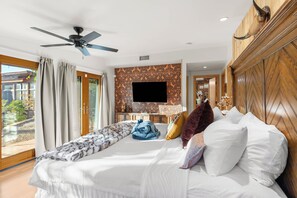 A hotel room with a bed, a ceiling fan, a television, and a view of the outdoors. - West Sedona 4BR retreat with hot tub, game room, and red rock views. (Sedona)