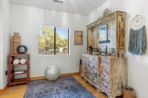 Quarto com uma janela ampla, um armário antigo, uma bola de yoga e um tapete estampado.