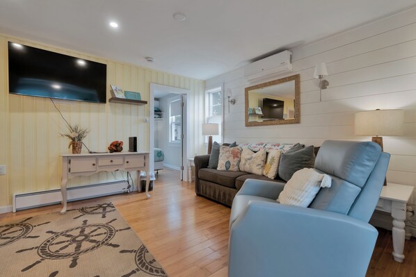 A living room with a flat-screen TV, a sofa, a coffee table, and a patterned rug.