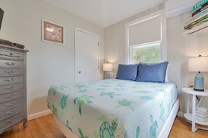 A bedroom with a bed, dresser, and a window.