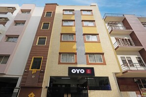 Un edificio de hotel de varios pisos con un cartel que indica 'OYO Hotel New Shelton Suites'.