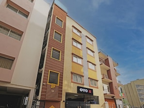 Un edificio de varios pisos con un llamativo letrero del hotel OYO, que indica que se trata de un hotel.