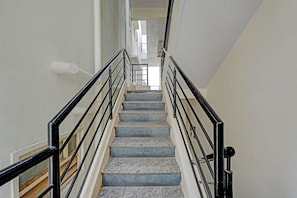 Una escalera de piedra con barandillas negras que sube.