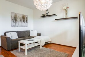 A modern living room with a grey sofa, white coffee table, and a decorative light fixture. - City Centre Home, Sauna & Parking By Lapland Host (Rovaniemi)