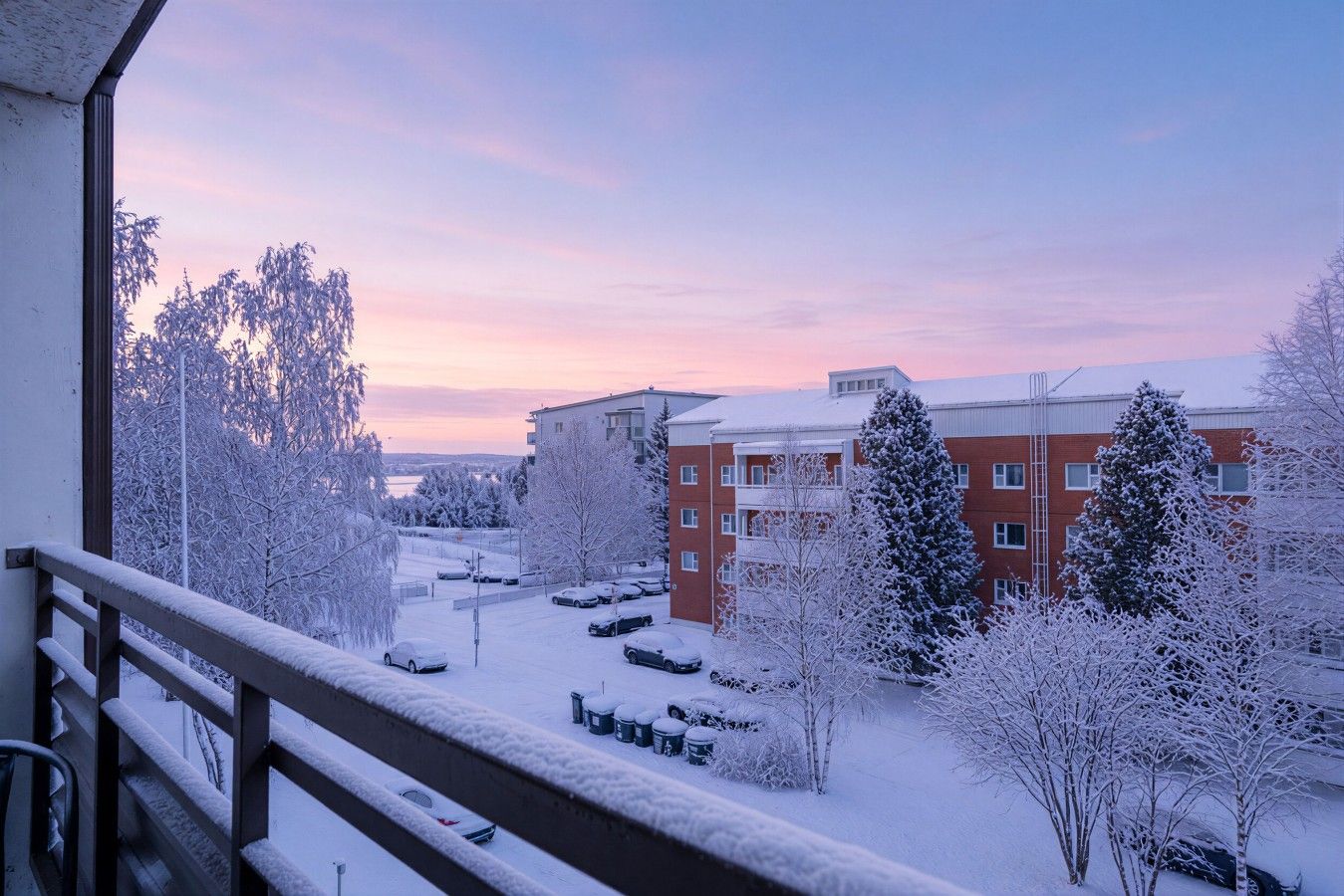 A snowy urban landscape with a building featuring multiple floors and a balcony.