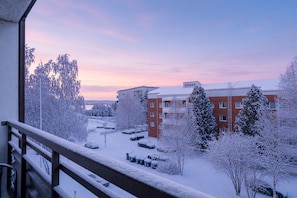 A snowy urban landscape with a building featuring multiple floors and a balcony. - City Centre Home, Sauna & Parking By Lapland Host (Rovaniemi)