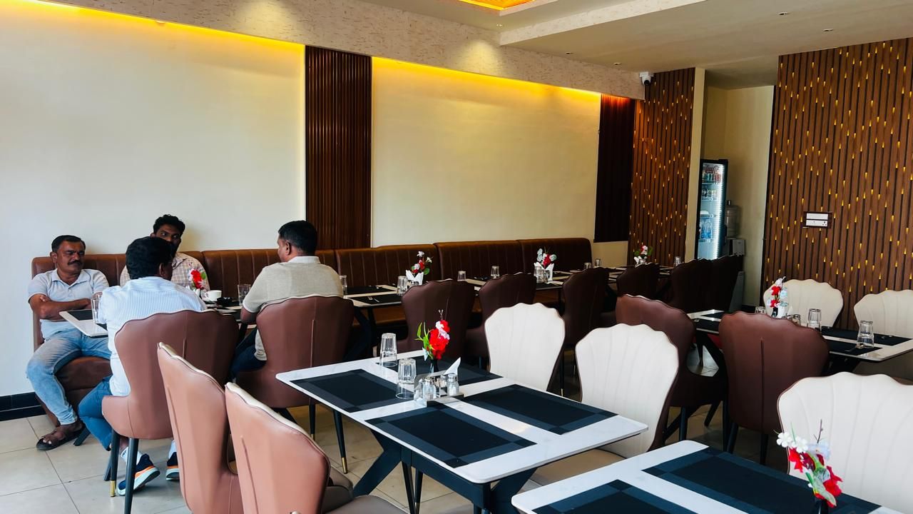 Een restaurant met zowel zitjes als tafels, waarvan sommigen een bloemstuk op het tafeltje hebben staan, en een modern interieur.
