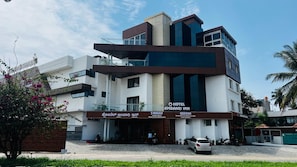 A multi-story hotel with a modern architectural design, featuring a prominent sign for the 'Hotel Ambari Inn.' - Hotel Ambaari Inn (Mandya)