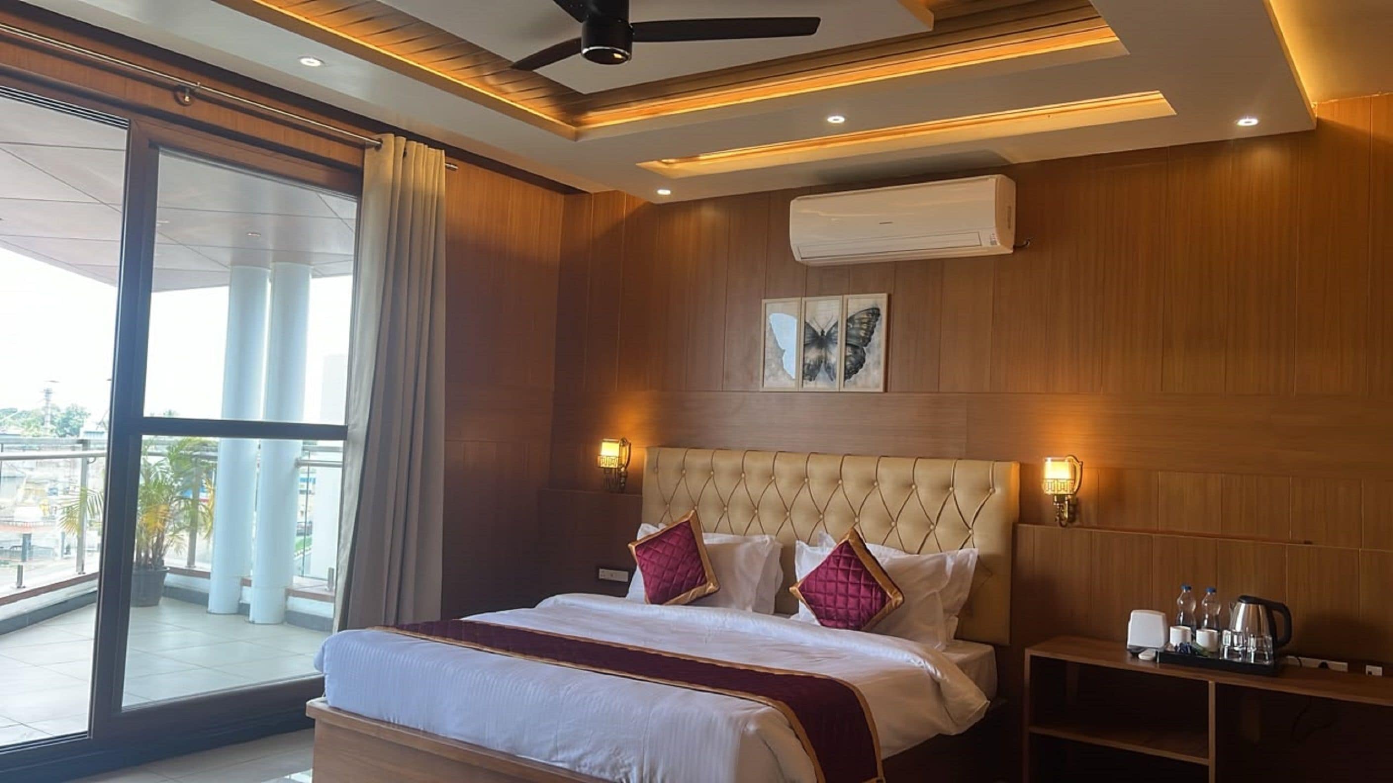 Habitación de hotel con una cama grande, ventilador de techo, aire acondicionado y vistas al exterior.