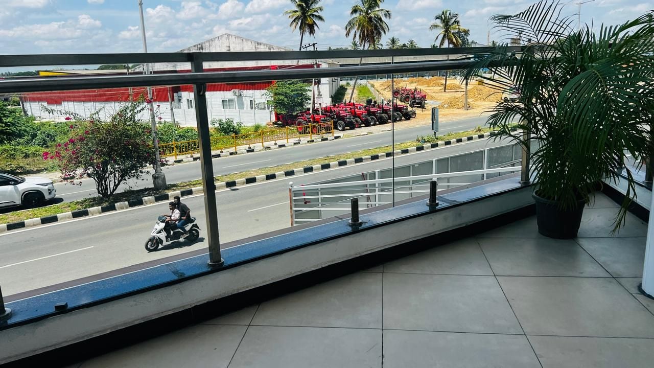 Un balcón con vista a una carretera, una motocicleta estacionada y una fila de tractores rojos.