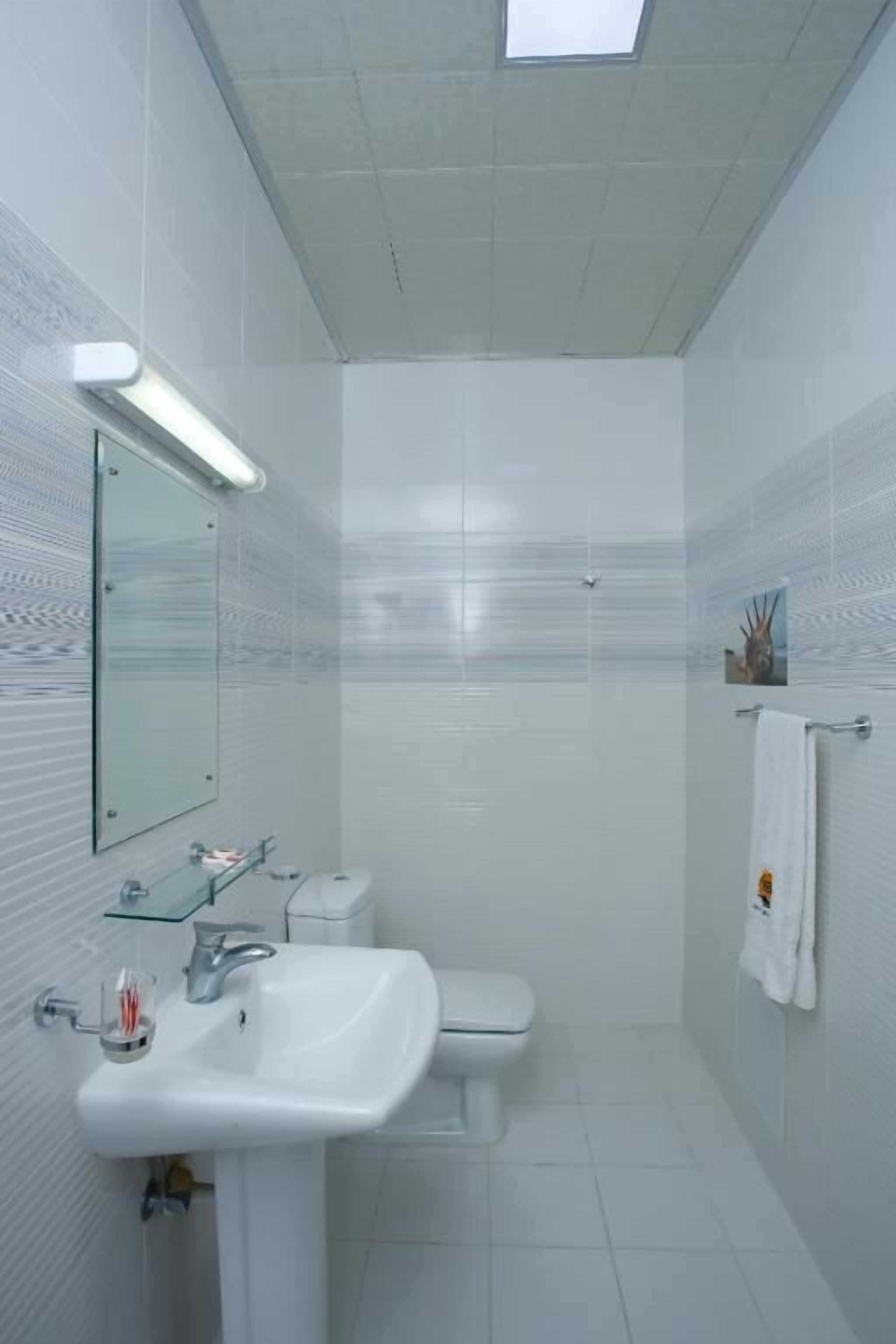 Un baño con lavamanos blanco, inodoro y zona de ducha.