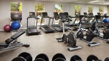Une salle de sport équipée de tapis de course, de vélos elliptiques et de poids libres.