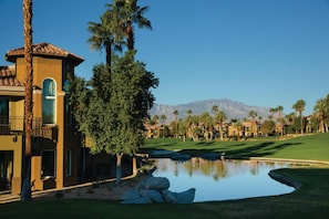 Un edificio residenziale con piscina, campo da golf e montagne sullo sfondo.