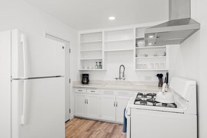 A modern kitchen with white cabinetry, a gas stove, a coffee maker, and a stainless steel range hood. - New! Bright Golden Hill Retreat | Pet Friendly (San Diego)