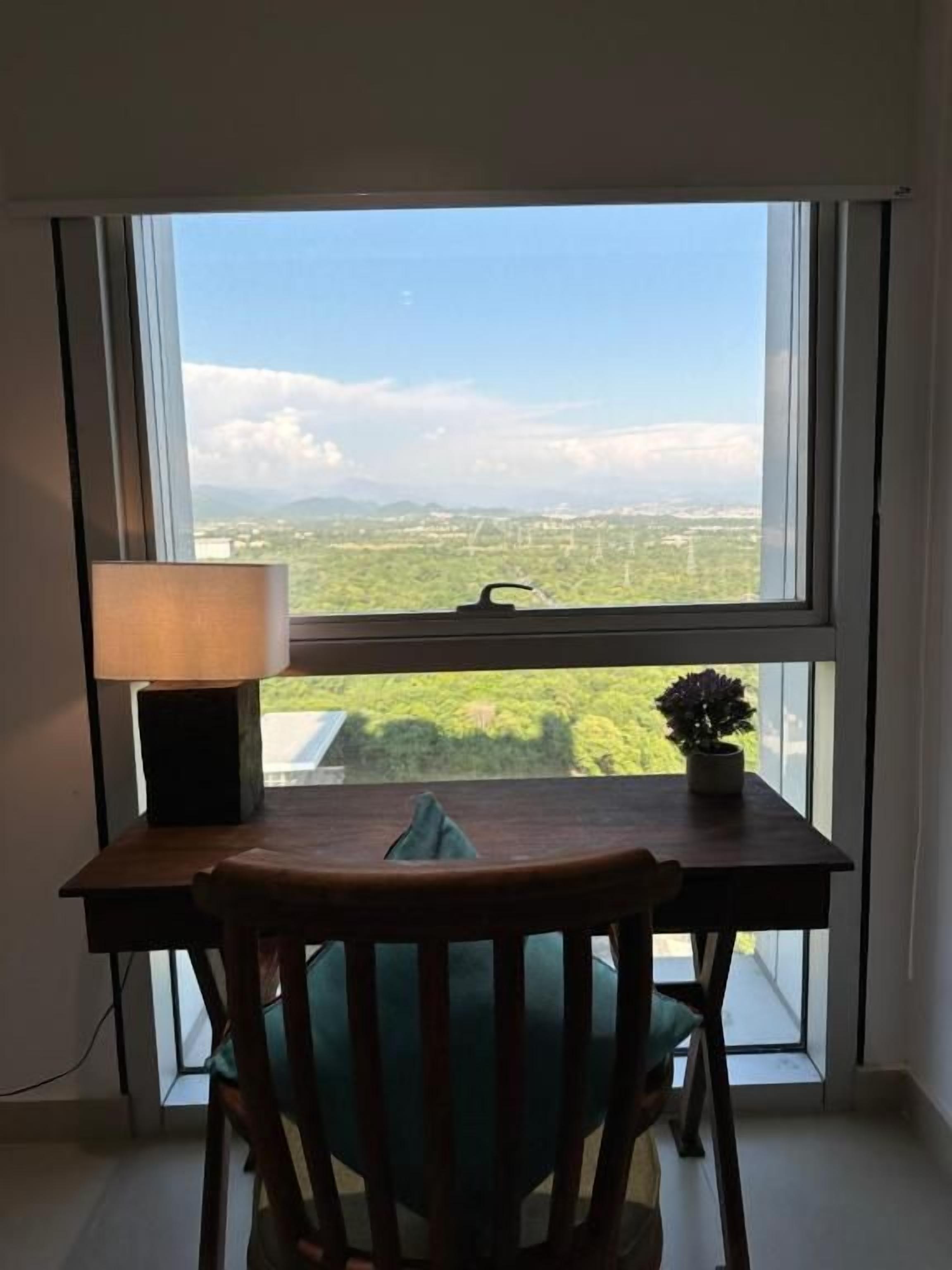 Een kamer met een tafel en een stoel, gericht op een groot raam met uitzicht op het landschap.
