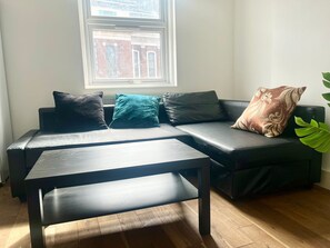 A modern living room with a sectional sofa, a coffee table, and a window with a view of a building. - Charming London Apartment With 2 Bedrooms (London)