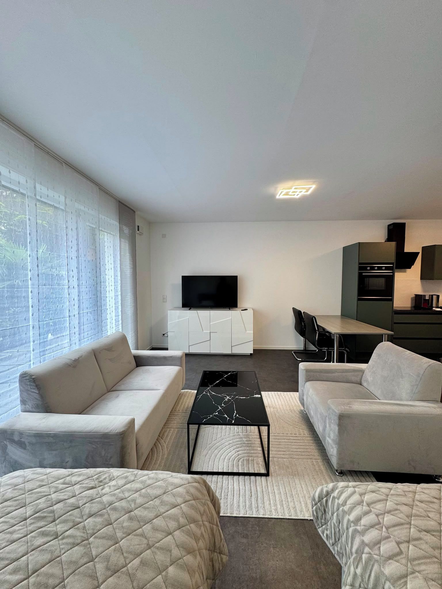 Ein modernes Wohnzimmer mit einer Couch, einem Couchtisch und einem Fernseher auf einer weißen Kommode.