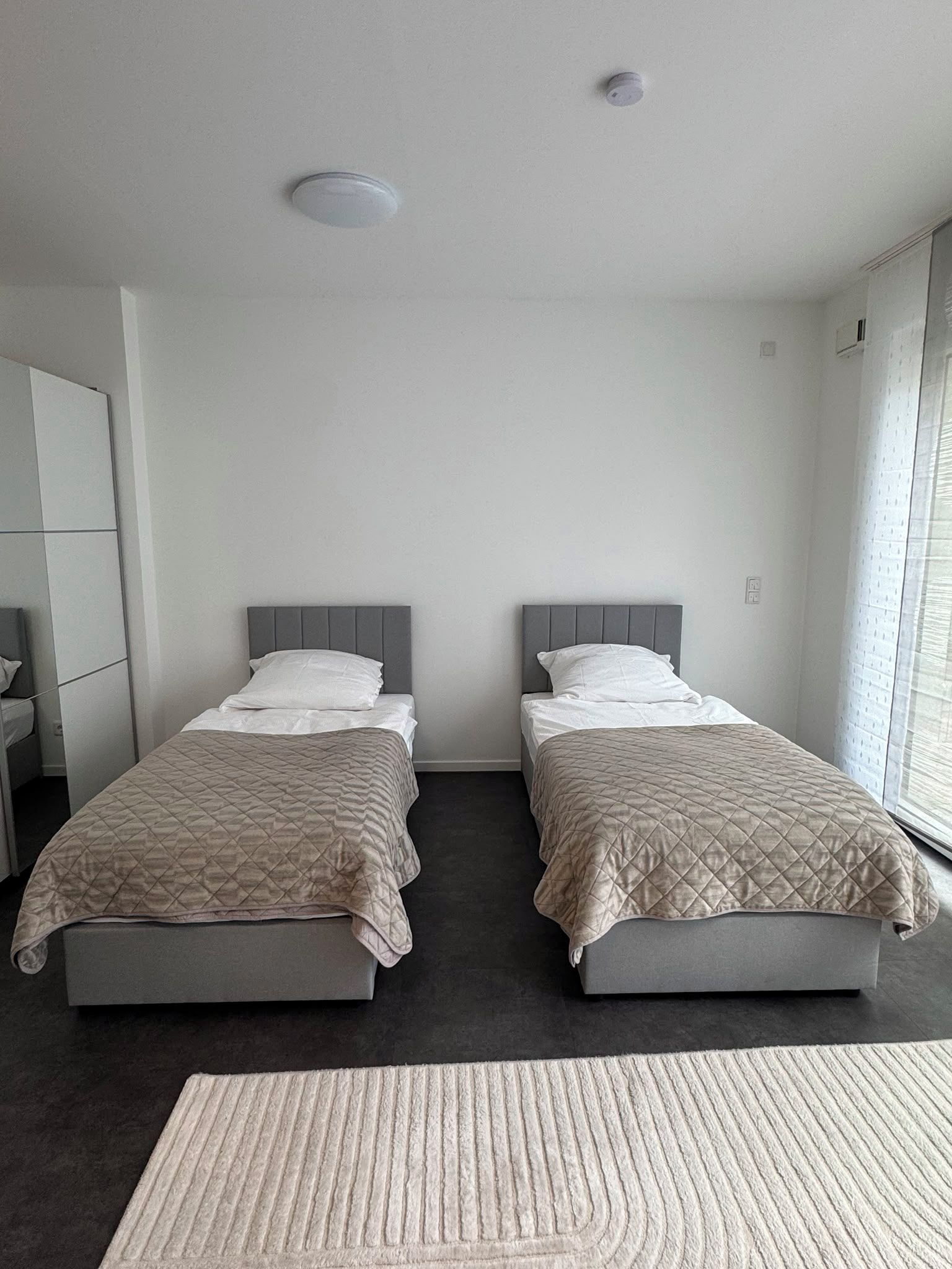 Ein Hotelzimmer mit zwei Betten, einem großen Fenster und einem dunklen Boden.