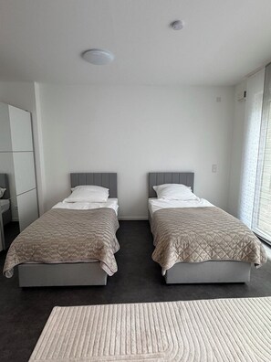 Ein Hotelzimmer mit zwei Betten, einem großen Fenster und einem dunklen Boden.