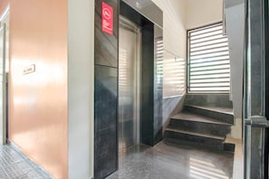 Um interior moderno com escada, um sinal vermelho indicando vigilância por câmeras de segurança e uma janela com persianas.