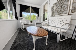 Ein Zimmer mit einem runden Holztisch, weißen Stühlen und einem gemusterten Teppich.