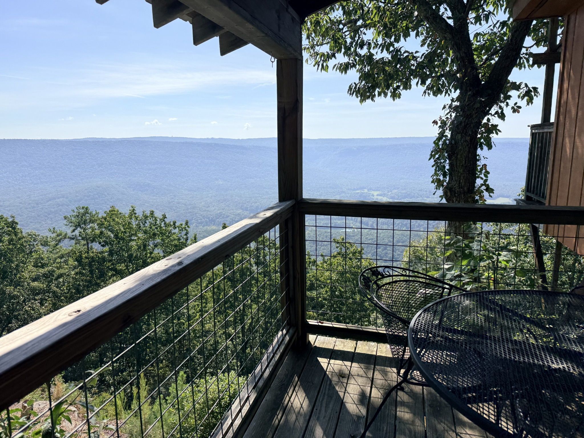 Eine Holterrasse mit Metallgeländer mit Blick auf eine gebirgige Landschaft.
