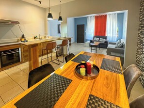 A modern kitchen with a wooden island, bar stools, and a dining table with black placemats. - Newly renovated one-bedroom, one-bath ground unit at Turquoise Condominiums (Playas Del Coco)