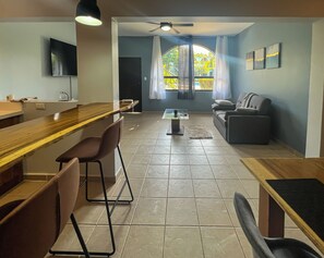 A modern living room with a sofa, a coffee table, and a TV mounted on the wall. - Newly renovated one-bedroom, one-bath ground unit at Turquoise Condominiums (Playas Del Coco)