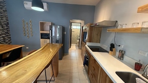 A compact kitchen with a wooden dining table, a built-in oven, and a stainless steel sink. - Newly renovated one-bedroom, one-bath ground unit at Turquoise Condominiums (Playas Del Coco)