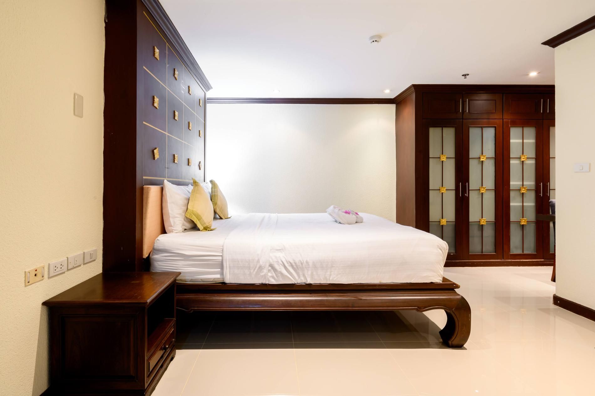 A bedroom with a large bed, a wardrobe, and a bathroom visible in the background.
