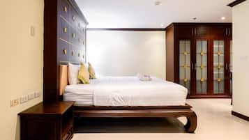A bedroom with a large bed, a wardrobe, and a bathroom visible in the background.