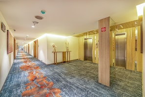 Un pasillo de hotel con alfombra estampada, puertas de madera y un letrero de prohibido fumar.