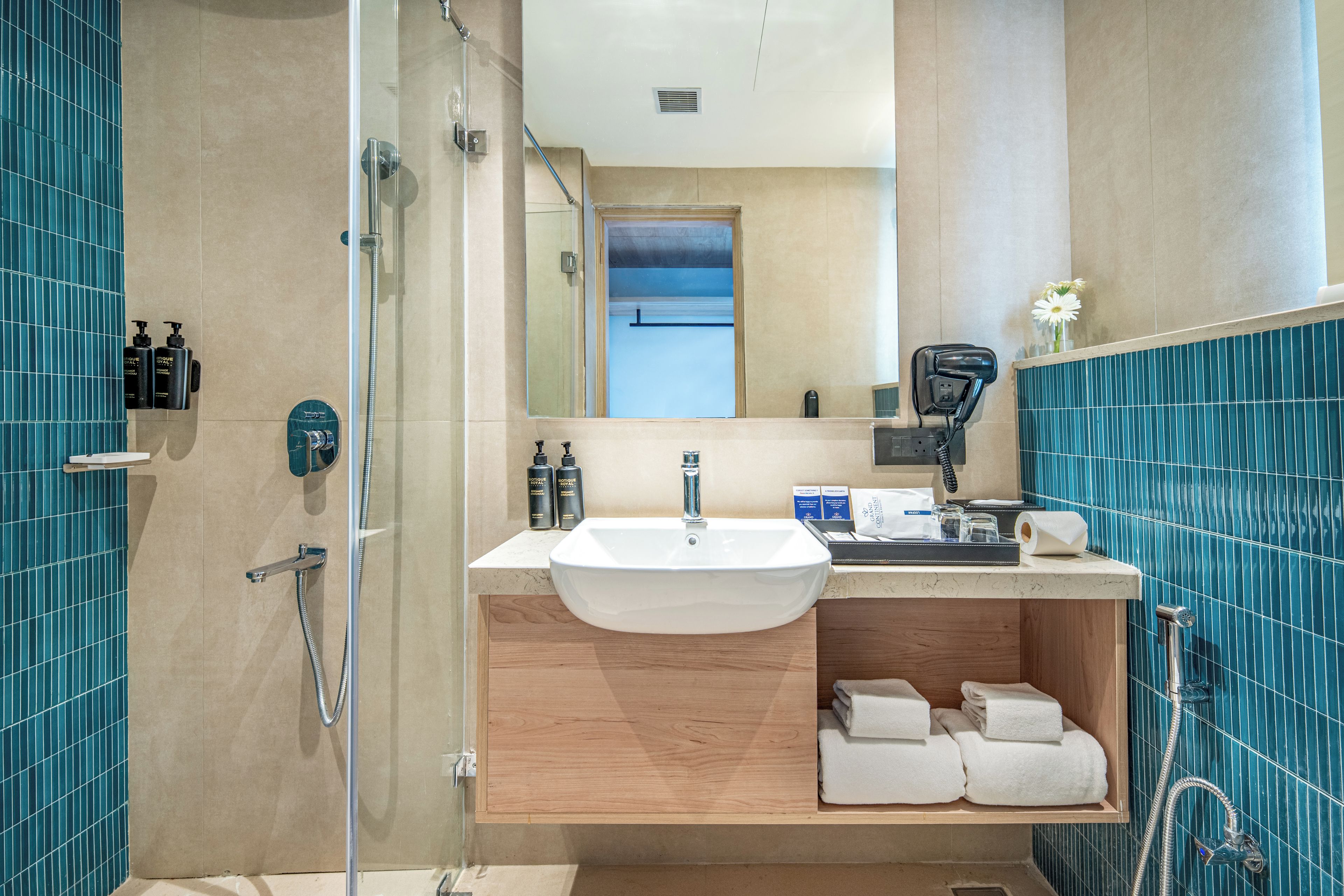 Un baño moderno con cabina de ducha de vidrio, un lavabo blanco y un mueble de tocador de madera.
