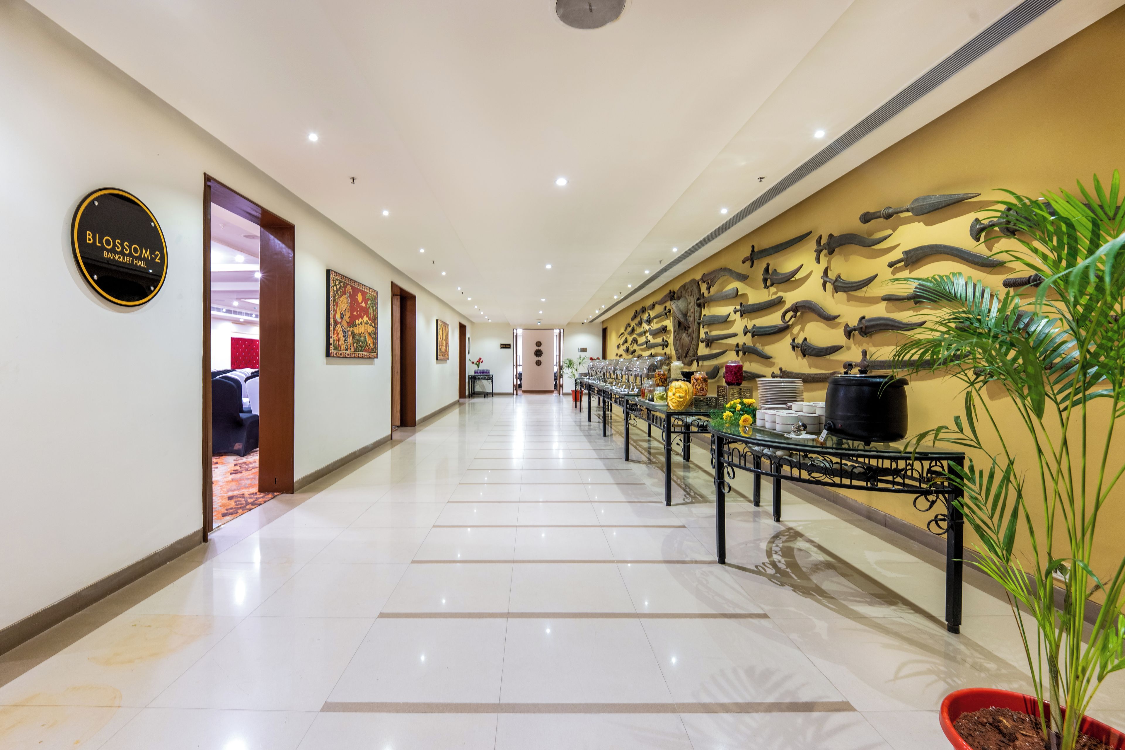 Pasillo de hotel con área de bufé, un letrero para el salón de banquetes y una pared con cubiertos colgantes.
