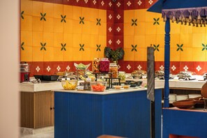 Montaje tipo bufé con diversos alimentos y una pared decorativa al fondo.