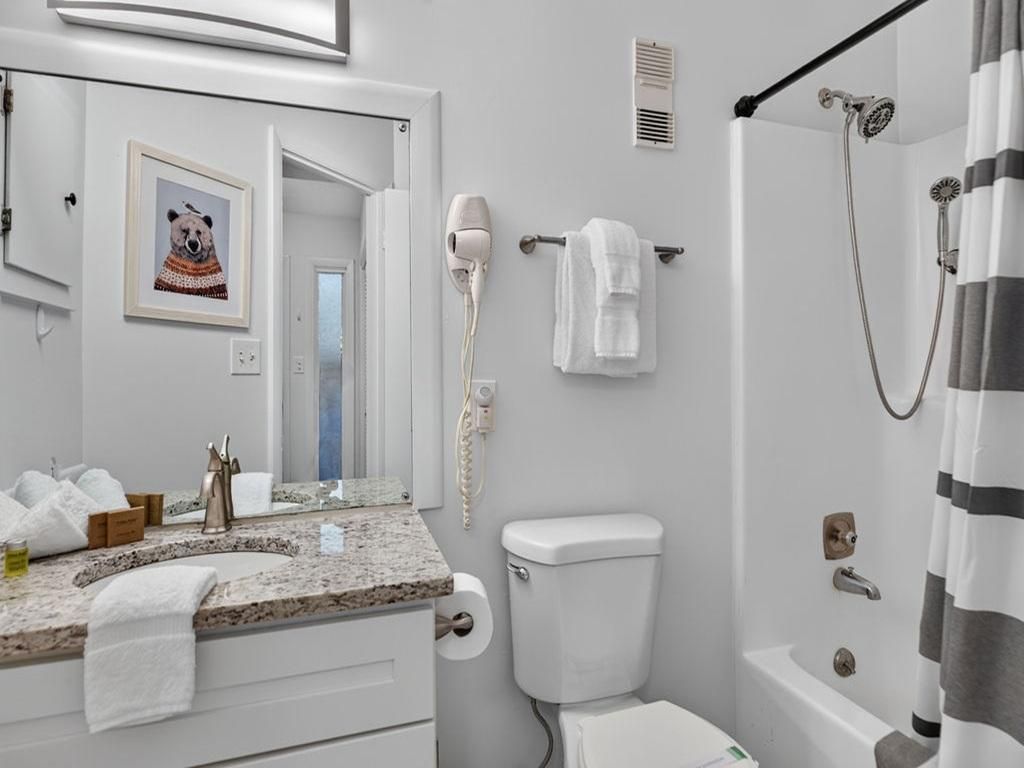 A bathroom with a sink, toilet, shower, and a towel rack.