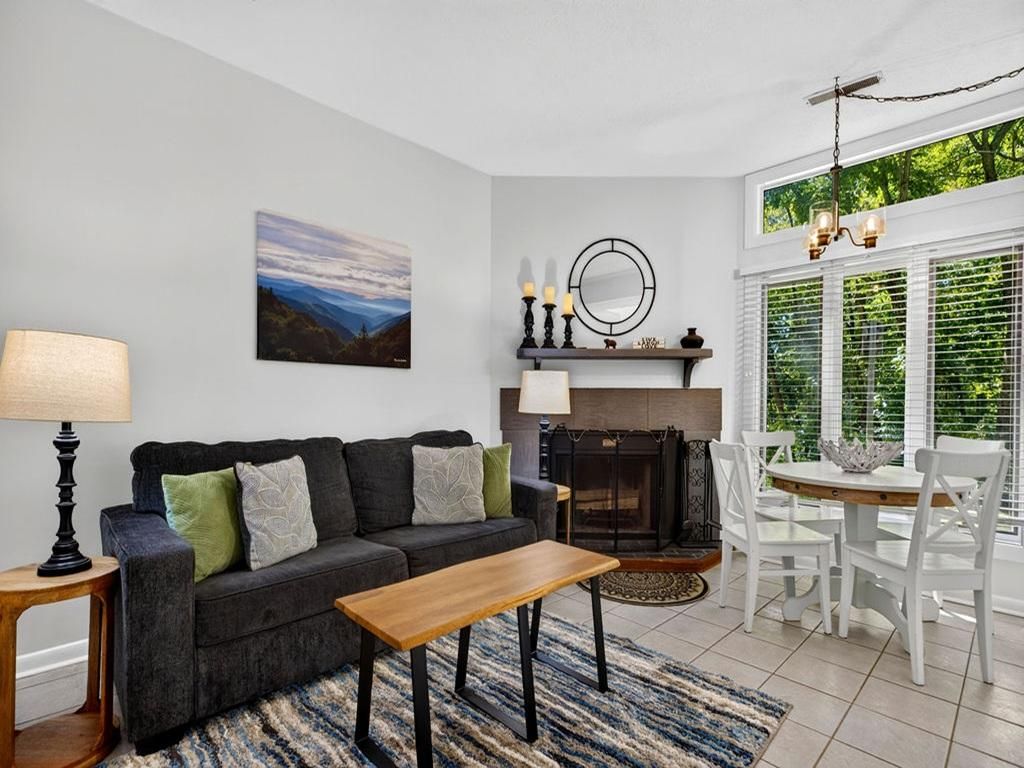 Un salon comprenant un canapé, une table basse, une cheminée et un coin repas avec des chaises et une table.