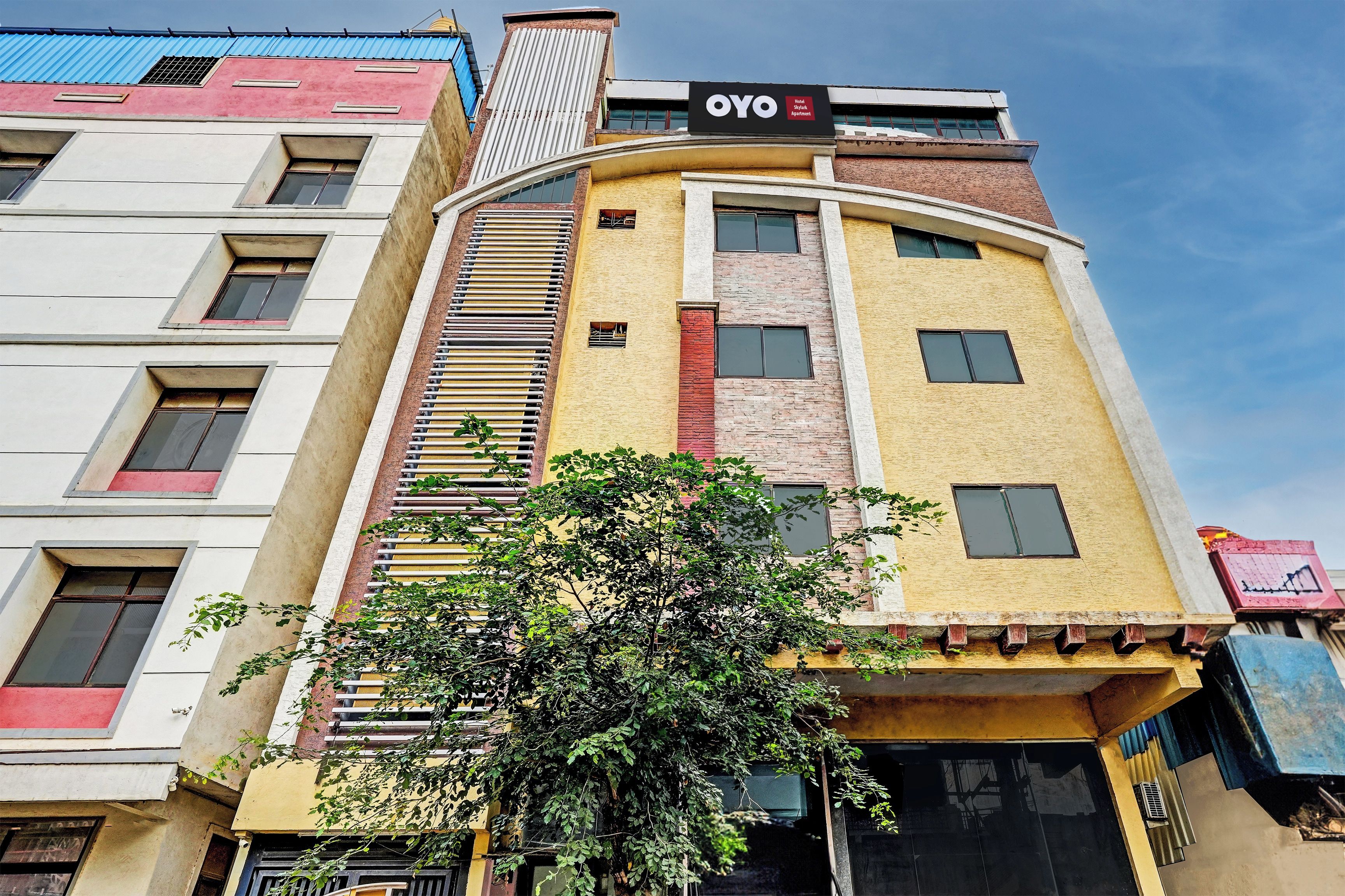 A multi-story building with a prominent 'OYO Hotel' sign, featuring a modern design with a mix of brick and plaster exteriors.