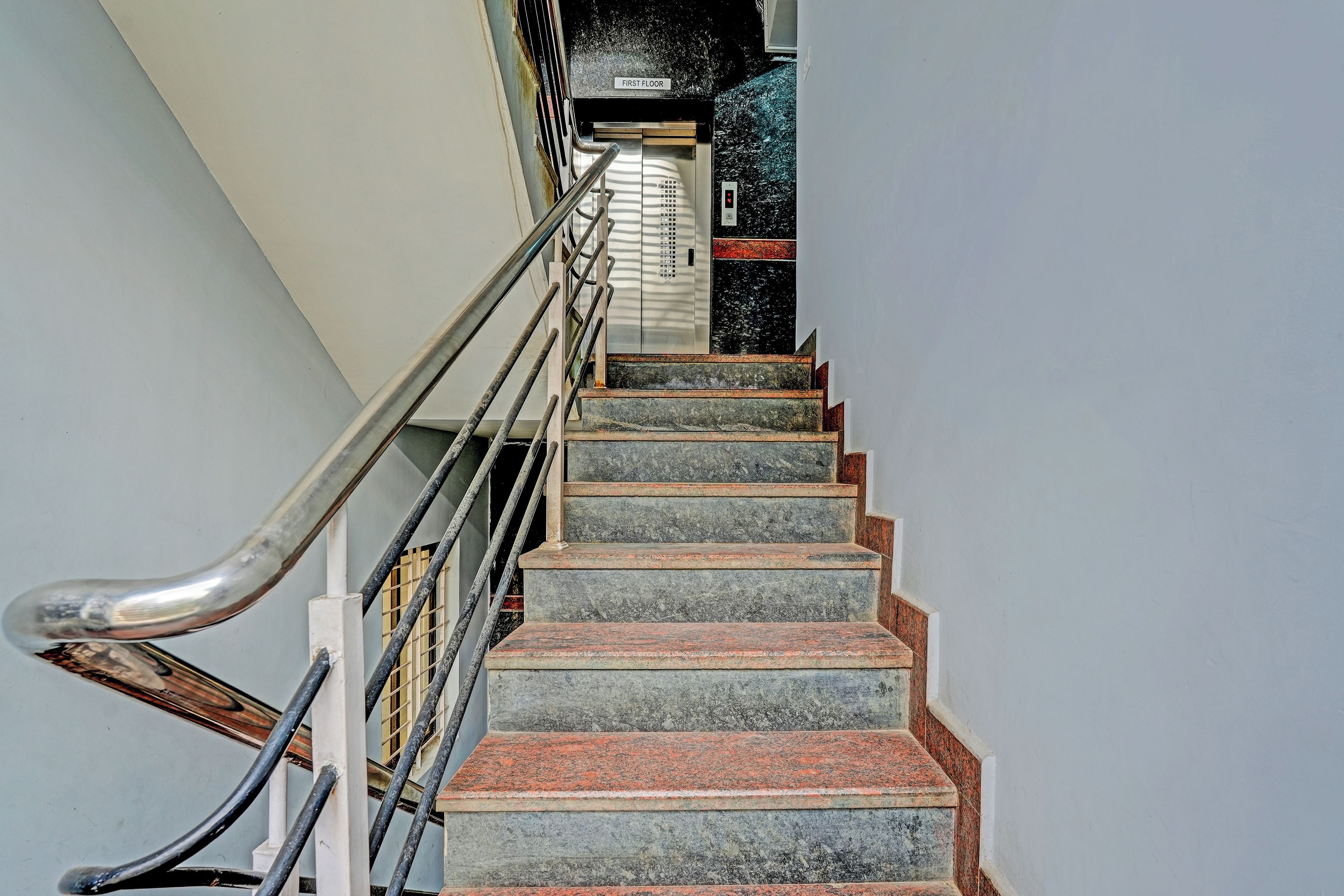 Una escala de pedra amb barana metàl·lica que mena a un ascensor.
