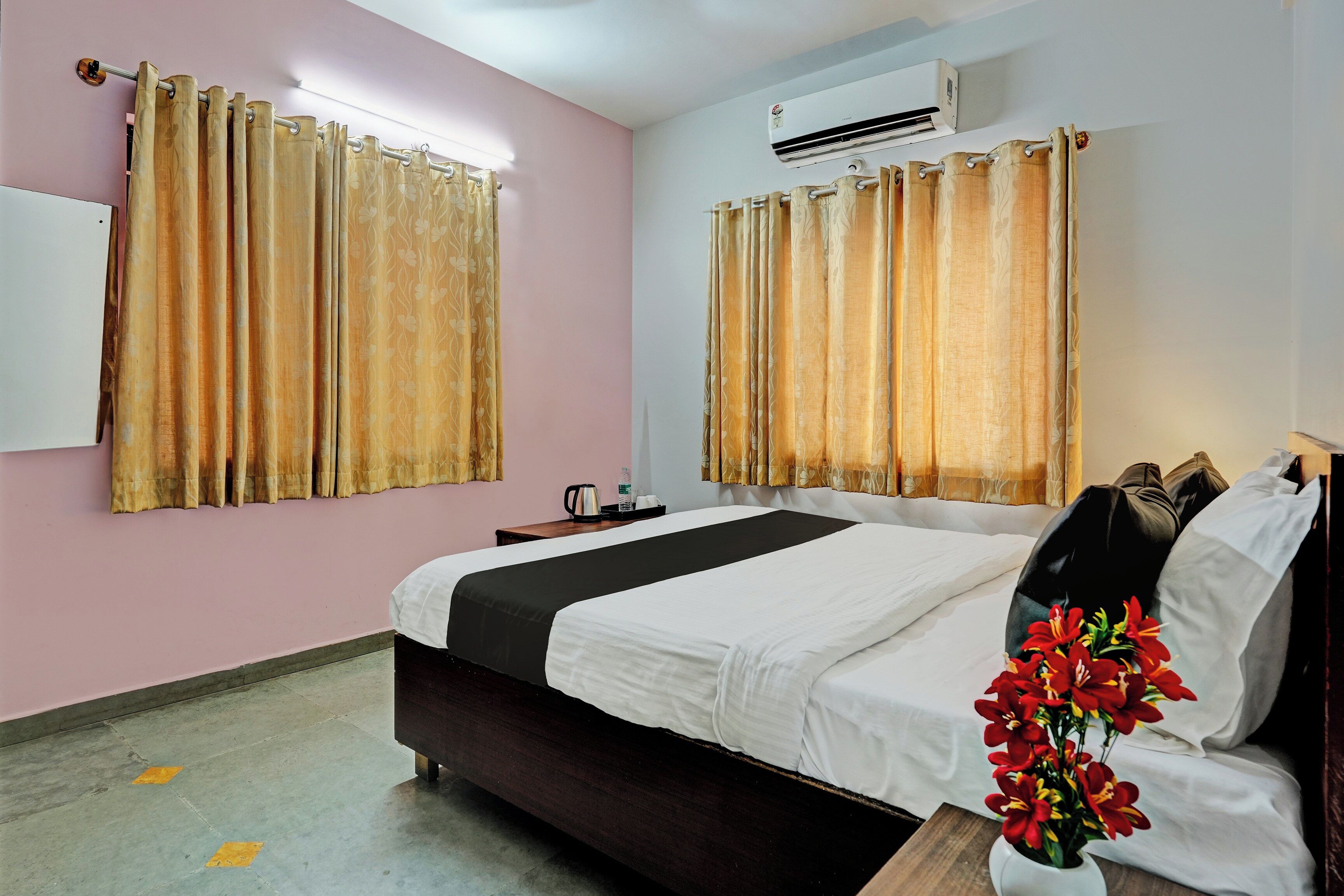 Una habitación de hotel con cama, mesita de noche, aire acondicionado y cortinas.
