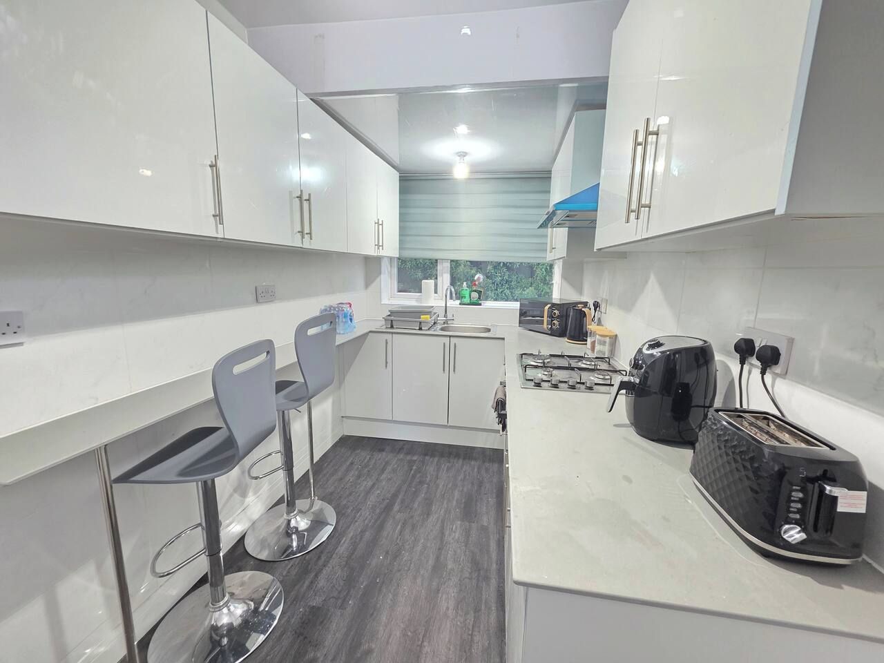 A compact kitchen with a bar area, modern appliances, and a view of greenery.
