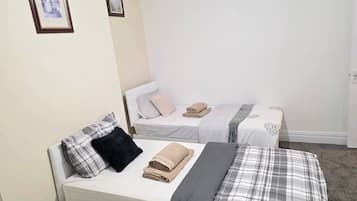 A bedroom with two beds, each with a pillow and a rolled towel.