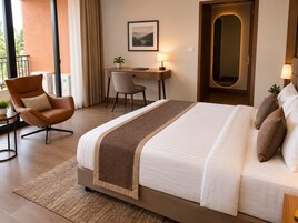Habitación de hotel con una cama grande, un escritorio, una silla y vistas al exterior.