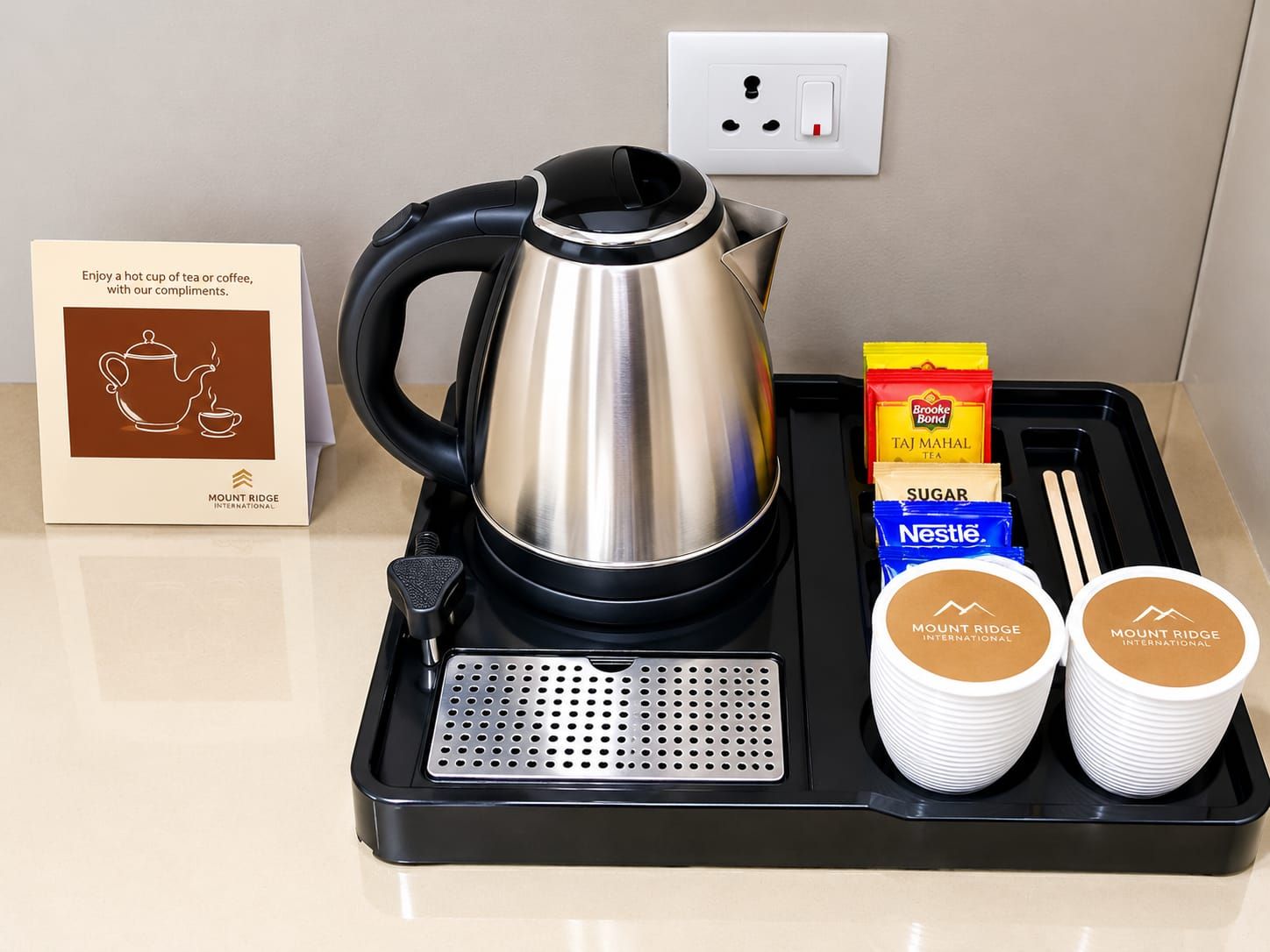 A tea kettle, sugar packets, tea bags, and two cups on a tray.