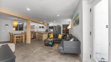 Een moderne woonkamer met een bank, salontafel en een eethoek.